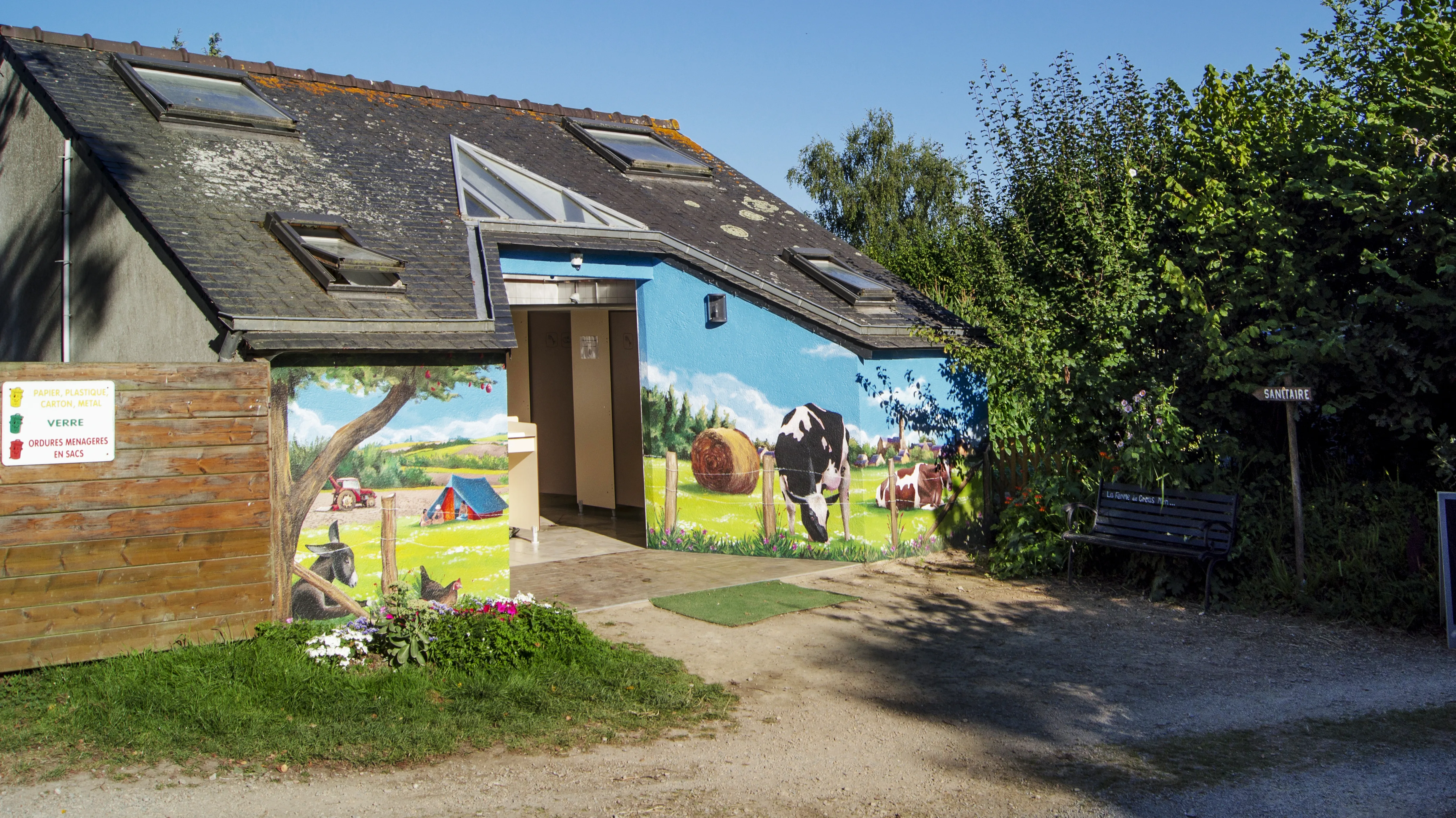 Scène de ferme bretonne (vaches, âne, poules, tracteur) peinte sur le bloc sanitaire du camping de Croas Men, après transformation.